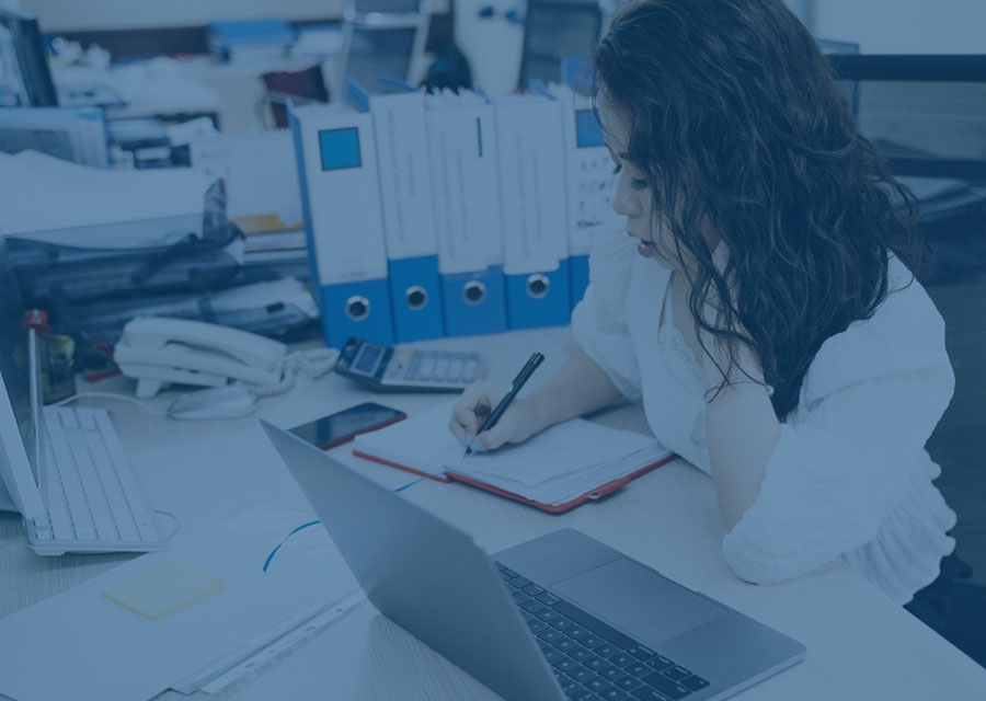 Woman working at a desk with laptop and writing